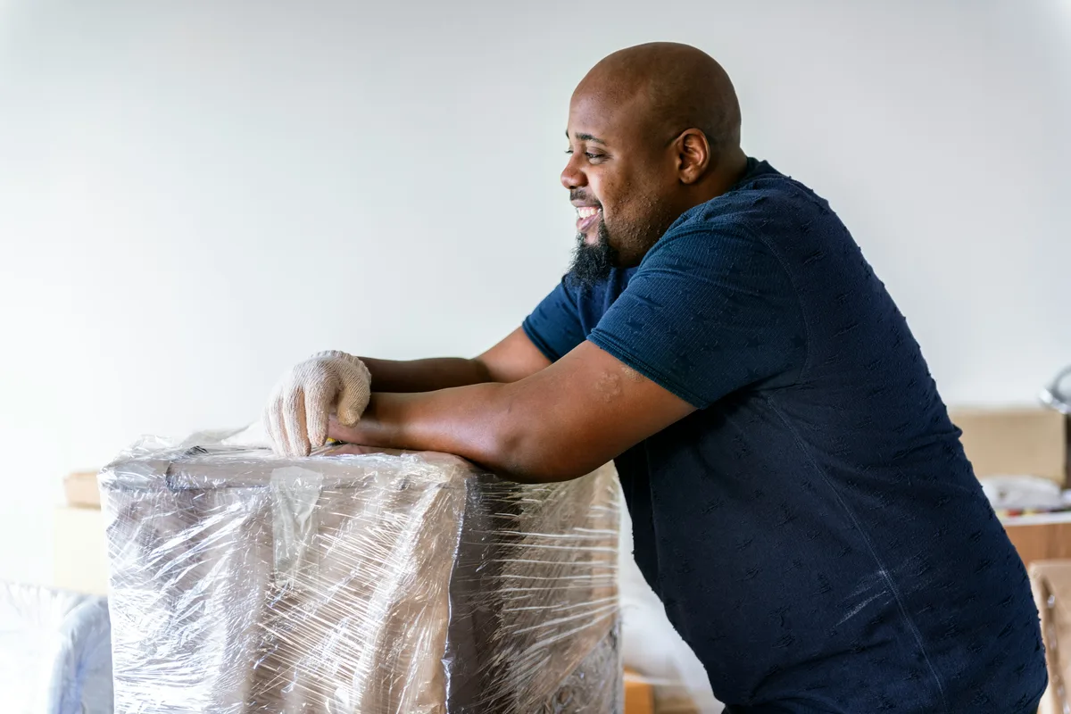 A mover wrapping furniture in protective film